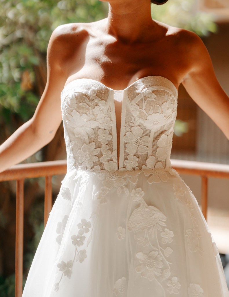 Le Love Club : robe 230 bustier façon corset graphique avec fente transparente au niveau de la poitrine, bas en tulle et fleurs xxl brodées et sequins brillants