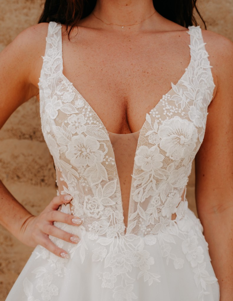 Le Love Club : robe 415 haut avec larges bretelles ornées de perles et de fleurs suggérant la poitrine par une fente ouverte jusqu'au nombril. Détails de sequins brillants